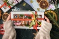 Woman hands hold gift box with decorated gingerbread men with white icing. Homemade traditional festive Christmas cookies. Flat Royalty Free Stock Photo