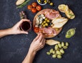 Woman hands hold a glass of wine. Appetizer, italian antipasto, ham, olives, cheese, bread, grapes, pear on dark stone background. Royalty Free Stock Photo