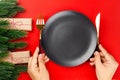 woman hands hold knife and fork near black empty plate on red table with Christmas trees and decorations Royalty Free Stock Photo