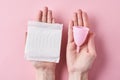 Woman hands hold sanitary pad and menstrual cup on a pink background Royalty Free Stock Photo