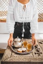 Woman hands hold silver tray with moroccan mint tea, cookies and vintage teapot Royalty Free Stock Photo