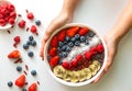 Woman hands holding an Acai Berry superfoods smoothies white bowl with chia seeds, strawberry, goji berry, coconut, blueberry