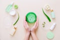 Woman hands holding aloe gel. Aloe vera leaves and cosmetic products on beige surface. Top view Royalty Free Stock Photo