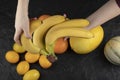 Woman hands holding banana cluster on black table