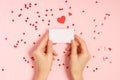 Woman hands holding blank Valentine card on pink table Royalty Free Stock Photo