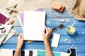 Woman hands holding blank white magazine with smart phone mockup on beach towel Royalty Free Stock Photo