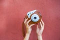 Woman hands holding a blue instax camera with a red wall on the background Royalty Free Stock Photo