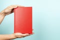 Woman hands holding book with blank red cover over light blue background. Education, back to school, self-learning, book Royalty Free Stock Photo