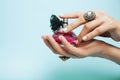 Woman hands holding bottle of perfume pink manicure and jewelry on blue background, cosmetic care concept Royalty Free Stock Photo