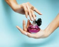 Woman hands holding bottle of perfume pink manicure and jewelry on blue background, luxury concept Royalty Free Stock Photo