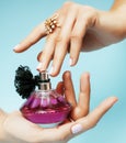 Woman hands holding bottle of perfume pink manicure and jewelry on blue background, luxury concept Royalty Free Stock Photo