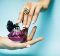 Woman hands holding bottle of perfume pink manicure and jewelry on blue background, luxury concept Royalty Free Stock Photo