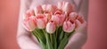 Woman hands holding a bouquet of tulips on a light pink background