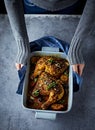 Woman hands holding a ceramik dish with oven-baked chicken legs