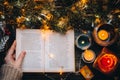 Woman hands holding Christmas Book. reading fairytale Story in cozy home evening. Christmas Holiday mood. New Eve candle lights on Royalty Free Stock Photo