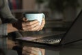 Woman hands holding coffee watching media on laptop Royalty Free Stock Photo