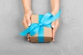 Woman hands holding craft paper gift box on gray background, top view Royalty Free Stock Photo