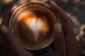 Woman hands holding cup of cappuccino coffee with heart shape. Royalty Free Stock Photo