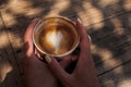 Woman hands holding cup of cappuccino coffee with heart shape. Royalty Free Stock Photo