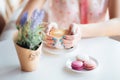 Woman hands holding cup of coffee. Macarons on table and lavender