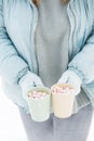 Woman Hands Holding Cup of Hot Chocolate with Marshmallow candies. Knitted mittens and Warm cocoa drink Royalty Free Stock Photo