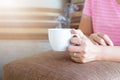 Woman hands holding a cup of hot coffee with smoke, In the morning under warm sunlight. Royalty Free Stock Photo