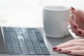 Woman hands holding cup on laptop keyboard Royalty Free Stock Photo