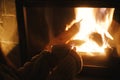 Woman hands holding cup of tea and warming up at cozy fireplace in dark evening room, close up. Fireplace heating in house,