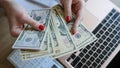 Woman hands holding dollar bills earned by working from laptop at home on Internet Royalty Free Stock Photo