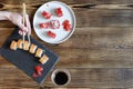 Woman hands holding fish sushi rolls with salmon, red caviar with chopsticks on gray black ceramic serving plate on wooden rustic Royalty Free Stock Photo