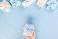 Woman hands holding gift or gift box decorated with confetti on blue pastel table top view. Flat composition for birthday or Royalty Free Stock Photo