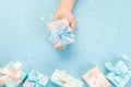 Woman hands holding gift or gift box decorated with confetti on blue pastel table top view. Flat composition for birthday or Royalty Free Stock Photo