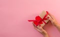 Woman hands holding gift with red ribbon and heart Royalty Free Stock Photo