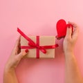 Woman hands holding gift with red ribbon and heart Royalty Free Stock Photo