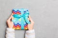 Woman hands holding gift wrapped and decorated with colored bow top view on grey cement table Holiday concept with copy space Royalty Free Stock Photo