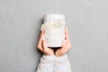 Woman hands holding gift wrapped and decorated with colored bow top view on grey cement table Holiday concept with copy space Royalty Free Stock Photo