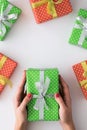 Woman hands holding green gift box on white background with other gifts. Top view, flat lay. Copyspace. Royalty Free Stock Photo