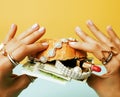 Woman hands holding hamburger with money, jewelry, cosmetic, social issue wealth concept close up