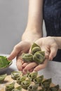 Woman hands holding just made tortelli - italian green filled pasta with ricotta