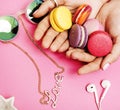 woman hands holding macaroons with lot of girl stuff on pink background, girls accessories concept close up Royalty Free Stock Photo