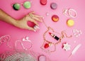 woman hands holding macaroons with lot of girl stuff on pink background, girls accessories concept close up Royalty Free Stock Photo