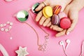 Woman hands holding macaroons with lot of girl stuff on pink background, girls accessories concept Royalty Free Stock Photo