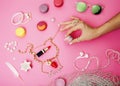 Woman hands holding macaroons with lot of girl stuff on pink background, girls accessories concept Royalty Free Stock Photo