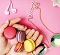 Woman hands holding macaroons with lot of girl stuff on pink background, girls accessories concept Royalty Free Stock Photo