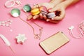 Woman hands holding macaroons with lot of girl stuff on pink background, girls accessories concept close up Royalty Free Stock Photo