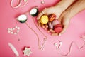 Woman hands holding macaroons with lot of girl stuff on pink background, girls accessories concept close up Royalty Free Stock Photo