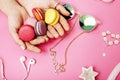 woman hands holding macaroons with lot of girl stuff on pink background, girls accessories concept Royalty Free Stock Photo