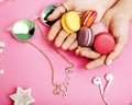 woman hands holding macaroons with lot of girl stuff on pink background, girls accessories concept close up Royalty Free Stock Photo