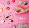 woman hands holding macaroons with lot of girl stuff on pink background, girls accessories concept close up Royalty Free Stock Photo