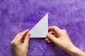 Woman hands holding made folded paper triangle on the violet surface Royalty Free Stock Photo